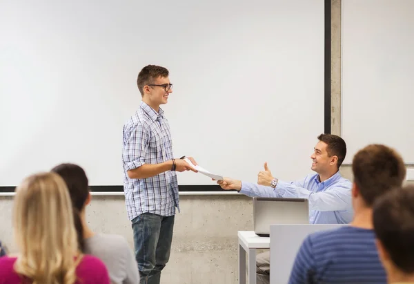 Groep studenten en lachende leraar met notitieblok Stockfoto