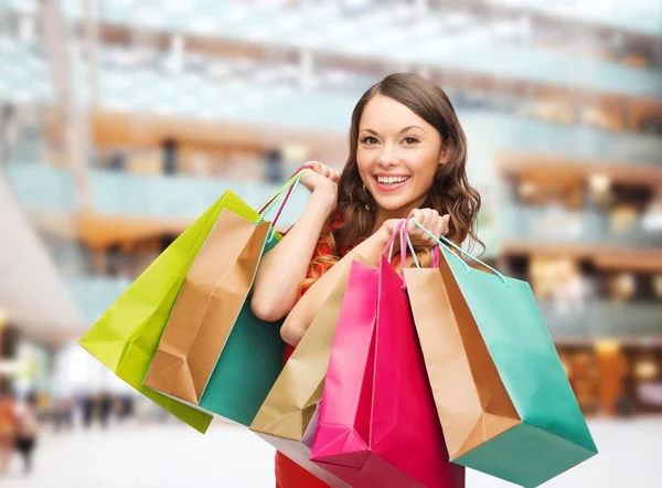 Mulher sorridente com sacos de compras coloridos — Fotografia de Stock