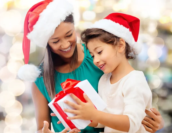 Gelukkig moeder en meisje in santa hoeden met doos van de gift — Stockfoto