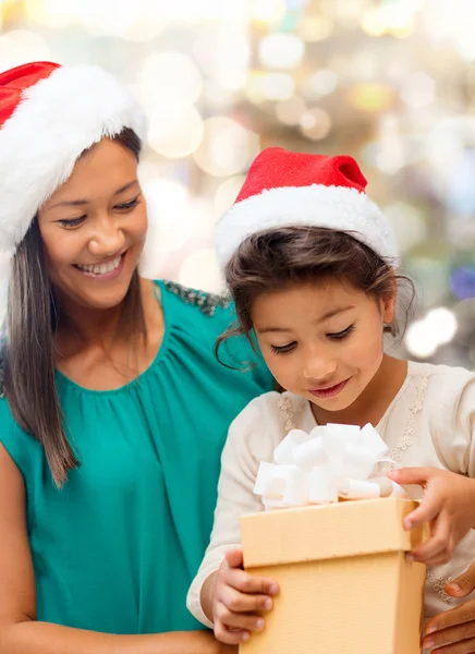 Gelukkig moeder en meisje in santa hoeden met doos van de gift — Stockfoto