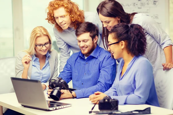 Equipo sonriente con portátil y cámara fotográfica en la oficina —  Fotos de Stock