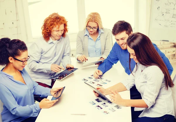Smiling team with table pc and papers working — Stock Photo, Image
