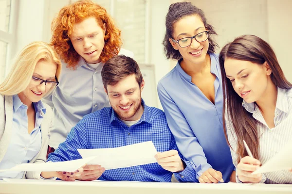 Lächelndes Team mit Papier im Büro — Stockfoto