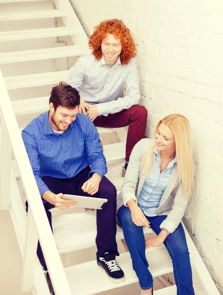 Team with tablet pc computer sitting on staircase — Stock Photo, Image