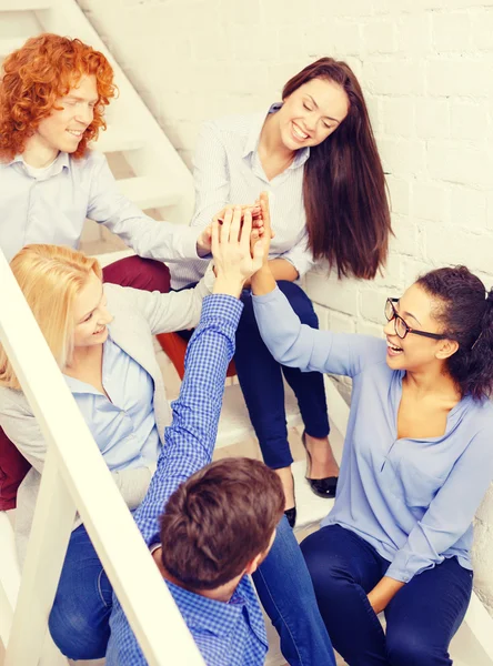 Equipo haciendo alta cinco gesto sentado en la escalera — Foto de Stock