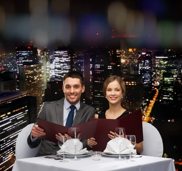 Smiling couple with menus at restaurant — Stock Photo, Image