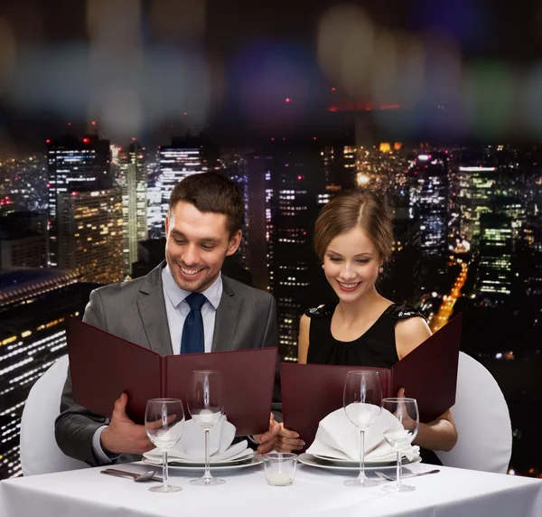 Concept de restaurant, de couple et de vacances - souriant couple avec menus au restaurant — Zdjęcie stockowe