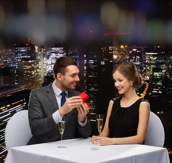 Excited young woman looking at boyfriend with box — Stock Photo, Image