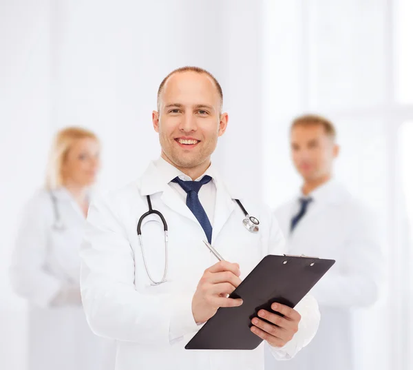 Usmívající se muž doktor s schránky a stetoskopem — Stock fotografie