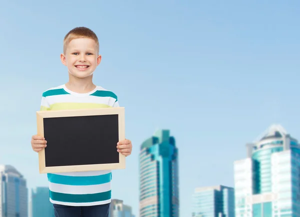 Smiling little boy holding blank black chalkboard — Stock Photo, Image