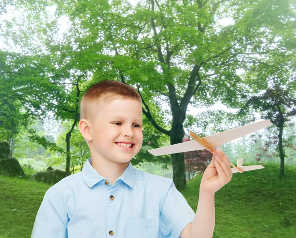 Menino sorrindo segurando um modelo de avião de madeira — Fotografia de Stock