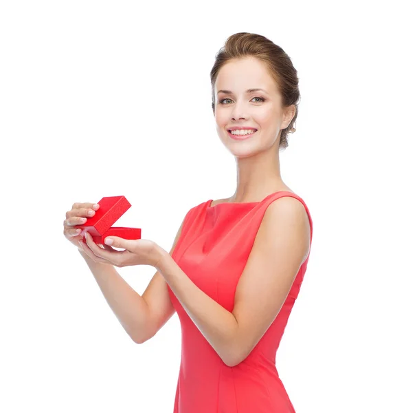 Usmívající se mladá žena v červených šatech s dárkovou krabicí — Stock fotografie