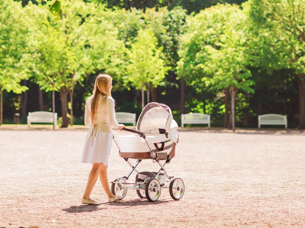 Glad mamma med barnvagn i park — Stockfoto