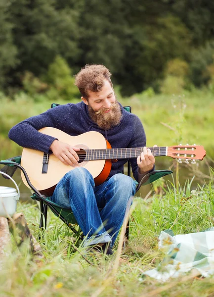 Smiling man with guitar and dixie in camping — Stock Photo, Image