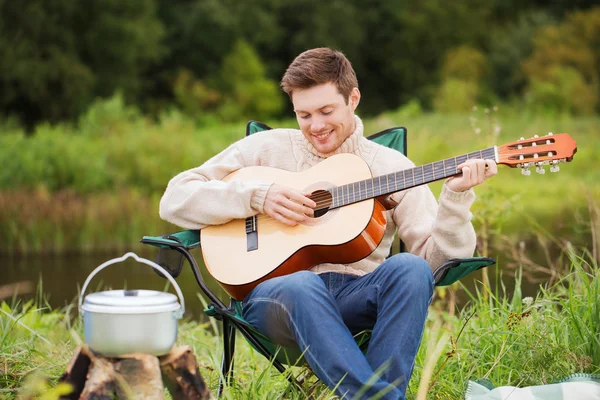 Smiling man with guitar and dixie in camping — Stock Photo, Image