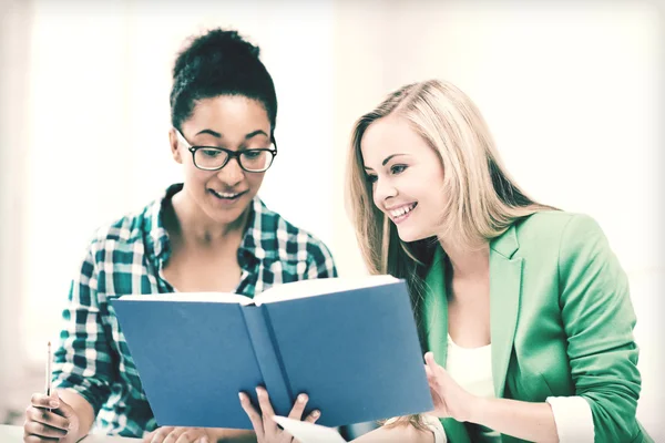 Smiling student girls reading book at school — Stock Photo, Image