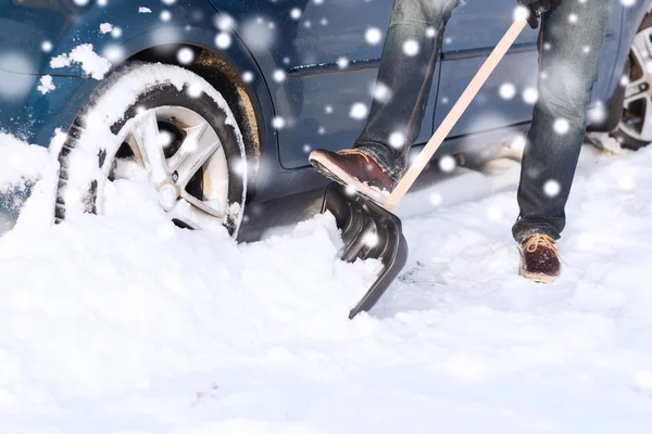 Adam araba yakınındaki kürek ile kar kazı closeup — Stok fotoğraf