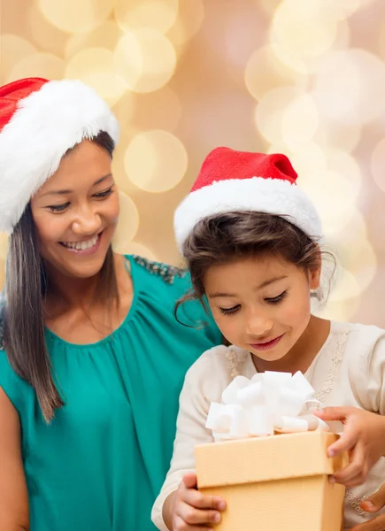 Gelukkig moeder en meisje in santa hoeden met doos van de gift — Stockfoto