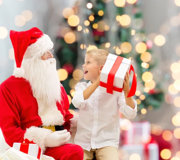 Niño sonriente con santa claus y regalos — Foto de Stock