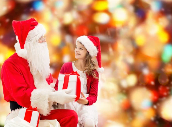 Smiling little girl with santa claus and gifts — Stock Photo, Image