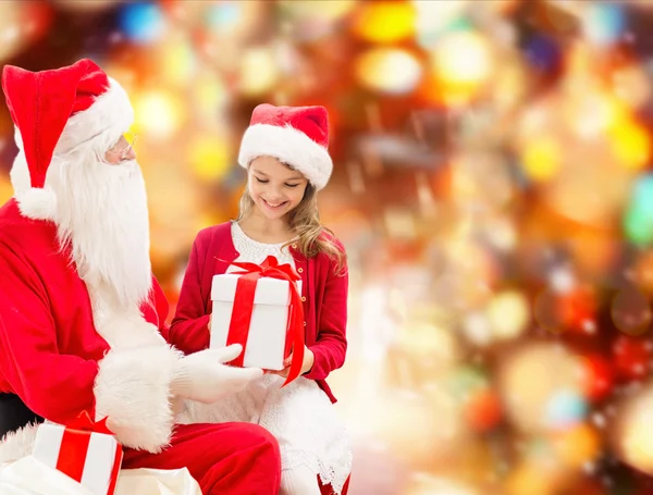 Smiling little girl with santa claus and gifts — Stock Photo, Image