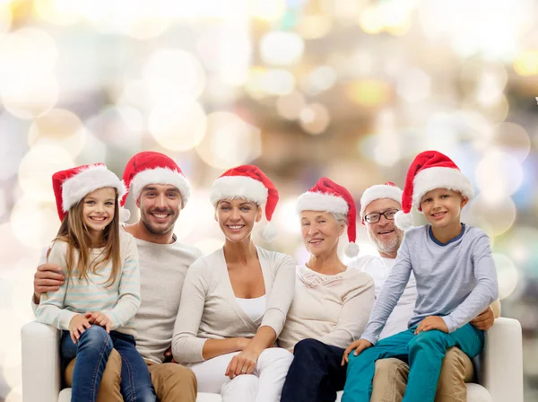 Família feliz em santa helper chapéus sentados no sofá — Fotografia de Stock