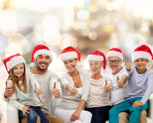 Família feliz em chapéus de santa mostrando polegares para cima — Fotografia de Stock