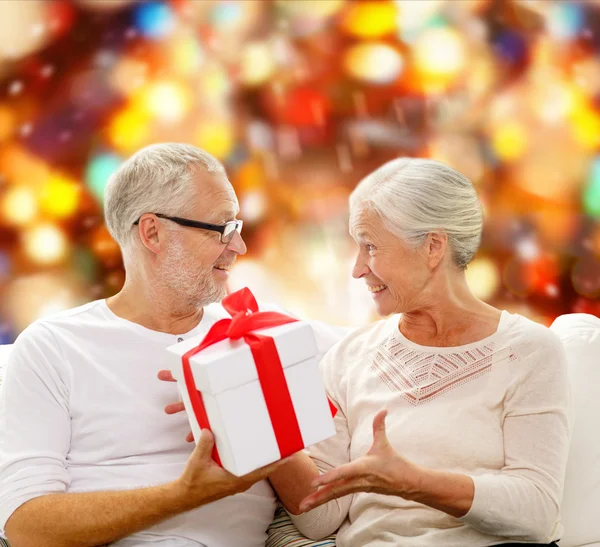 Ευτυχισμένο ζευγάρι ηλικιωμένων με κουτί δώρου στο σπίτι — Φωτογραφία Αρχείου
