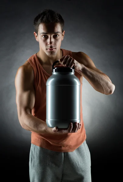 Jovem fisiculturista masculino segurando frasco com proteína — Fotografia de Stock