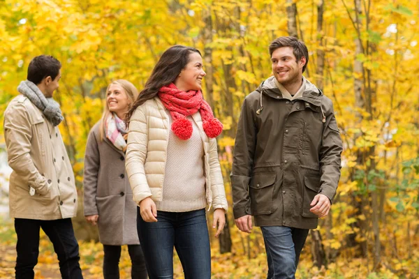 Group of smiling men and women in autumn park — Stock Photo, Image