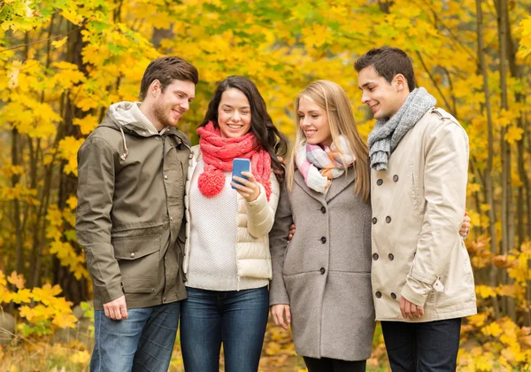 Uśmiechnięty znajomych ze smartfonów w parku — Zdjęcie stockowe