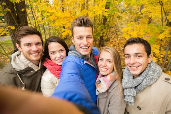 Group of smiling men and women in autumn park — Stock Photo, Image