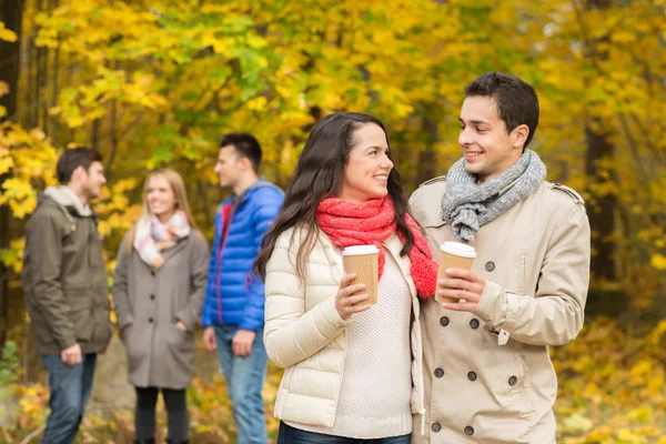 Grupp av leende vän med kaffekoppar i park — Stockfoto