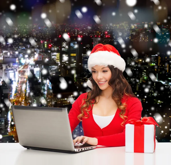 Smiling woman with gift box and laptop — Stock Photo, Image