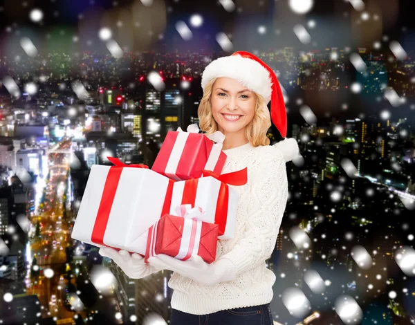 Smiling young woman in santa helper hat with gifts — Stock Photo, Image