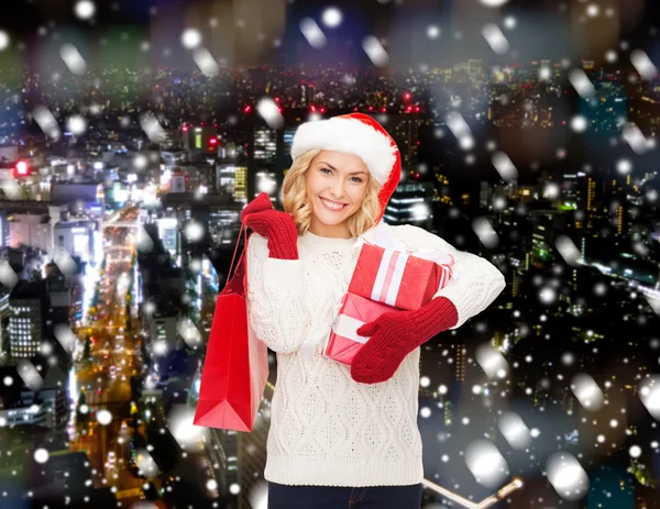 Glimlachend jonge vrouw in helper kerstmuts met geschenken — Stockfoto