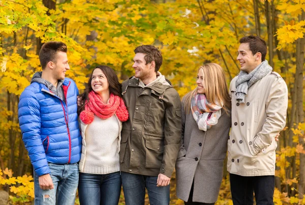 Grupo de hombres y mujeres sonrientes en el parque de otoño —  Fotos de Stock