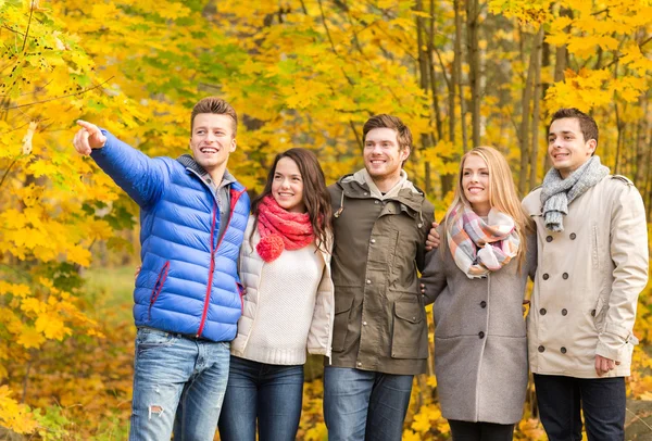 Group of smiling men and women in autumn park — Stock Photo, Image