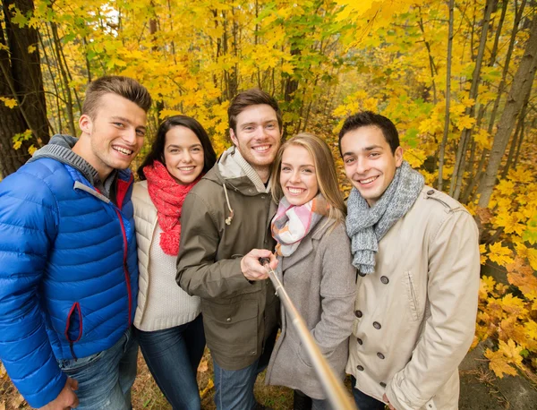 Amigos sonrientes con smartphone en el parque de la ciudad — Foto de Stock