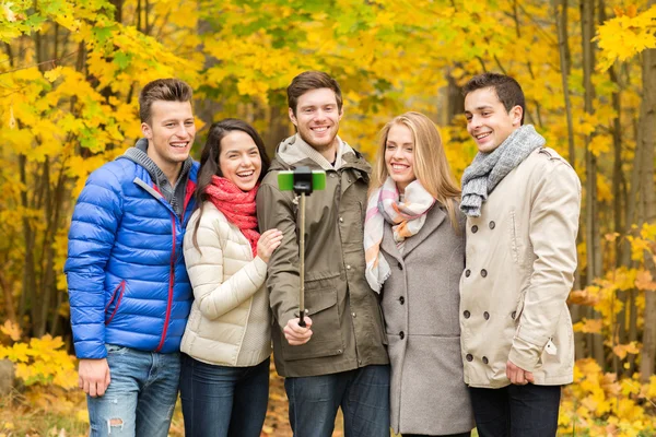 Amigos sonrientes con smartphone en el parque de la ciudad — Foto de Stock