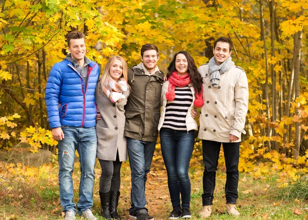 Grupo de hombres y mujeres sonrientes en el parque de otoño Imagen De Stock