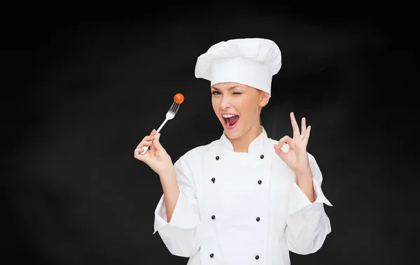 Uśmiechnięta kobieta kucharz z widelcem i pomidorów — Zdjęcie stockowe