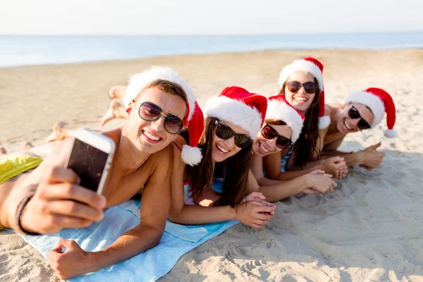 Gruppe von Freunden in Weihnachtsmützen mit Smartphone — Stockfoto