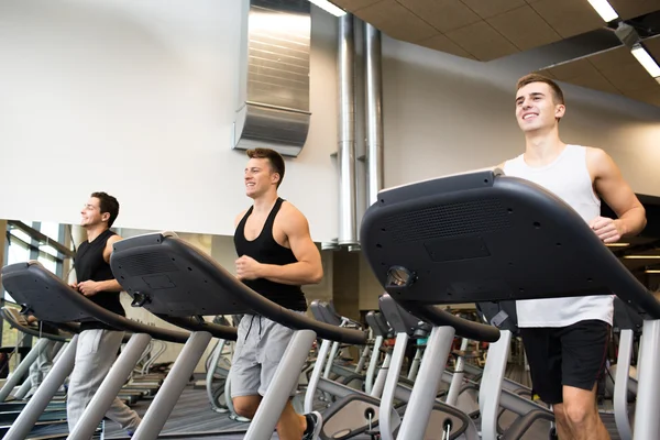 Lachende mannen uitoefenen op loopband in de sportschool — Stockfoto