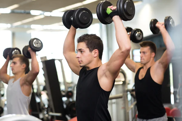 Groupe d'hommes avec haltères dans la salle de gym — Photo