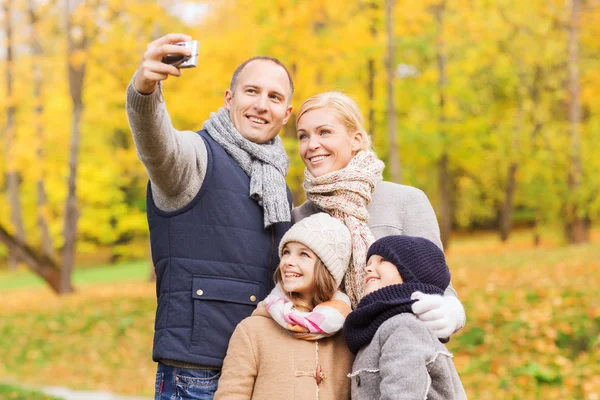 Família feliz com câmera no parque de outono — Fotografia de Stock