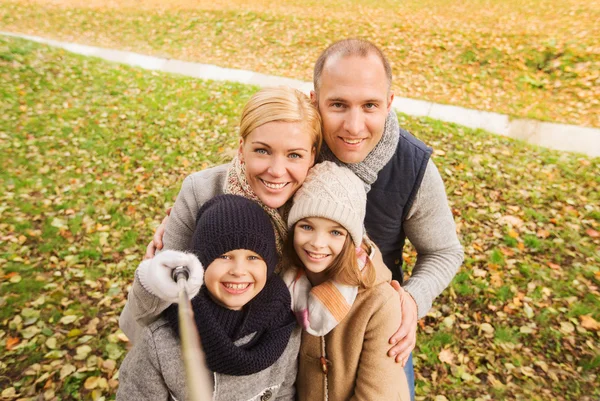 Famiglia felice con bastone selfie nel parco autunnale — Foto Stock