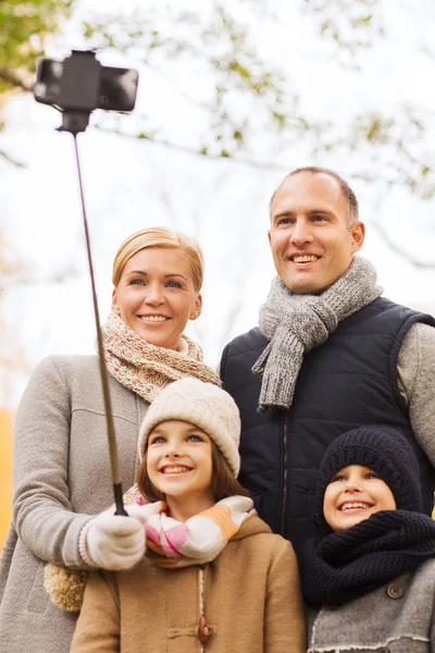 Happy family with smartphone and monopod in park — Stock Photo, Image