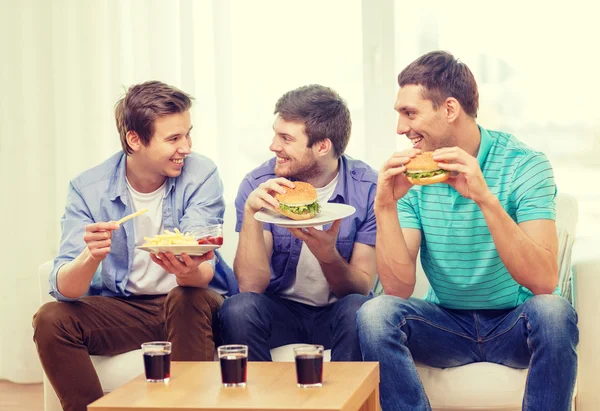 Lächelnd Freunde mit Soda und Hamburger zu Hause — Stok fotoğraf