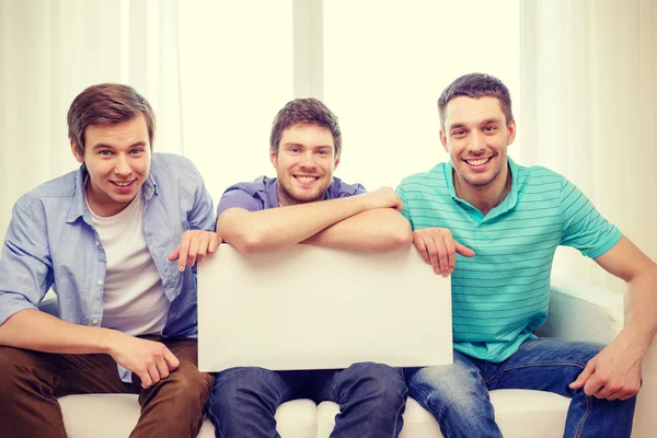 Улыбающиеся друзья мужчины держат белую пустую доску — стоковое фото